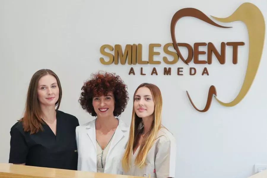 Equipo de recepción de SmilesDent Alameda junto al logo de la clínica